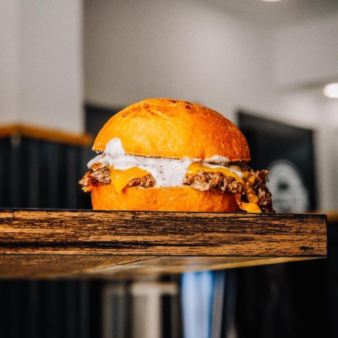 Hamburguesa gourmet sin gluten de Atípico Triana, elaborada con carne de retinto, queso cheddar y salsas caseras, 100% libre de gluten